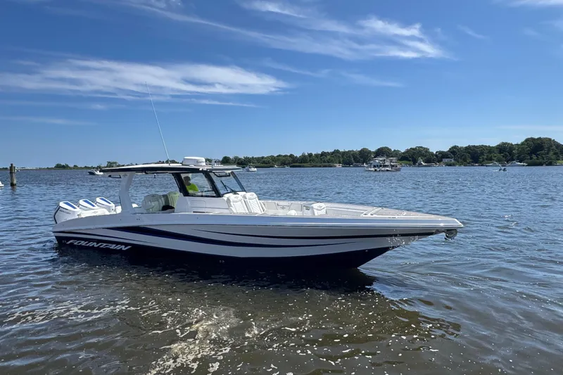 Yacht Photos Pics 2025 Fountain 38 SCX boat on a sunny lake, showcasing sleek design and powerful engines.
