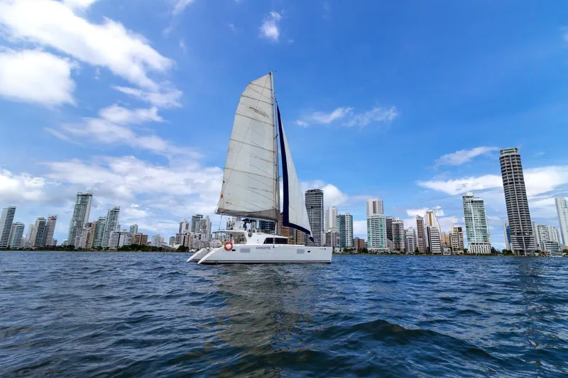 Agm26a09z3354 Yacht Photos Pics Sailboat Lagoon 440 (2010) cruising near city skyline under blue sky.
