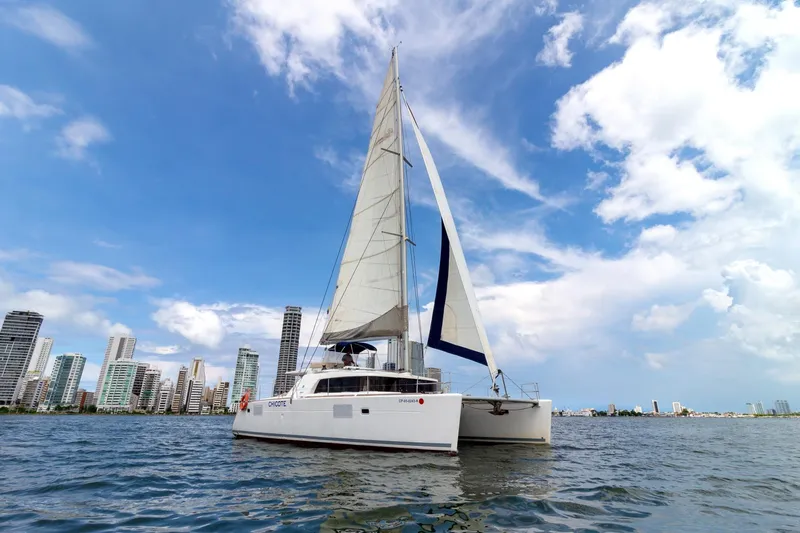Agm26a09z3354 Yacht Photos Pics Sailing catamaran Lagoon 440, 2010 model, on water with city skyline background.