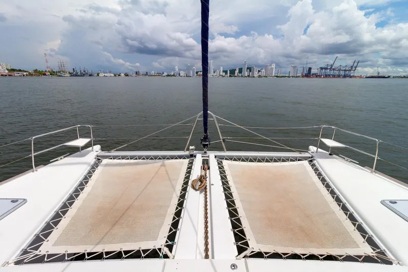 Agm26a09z3354 Yacht Photos Pics Front deck view of 2010 Lagoon 440 catamaran with city skyline and cloudy sky.