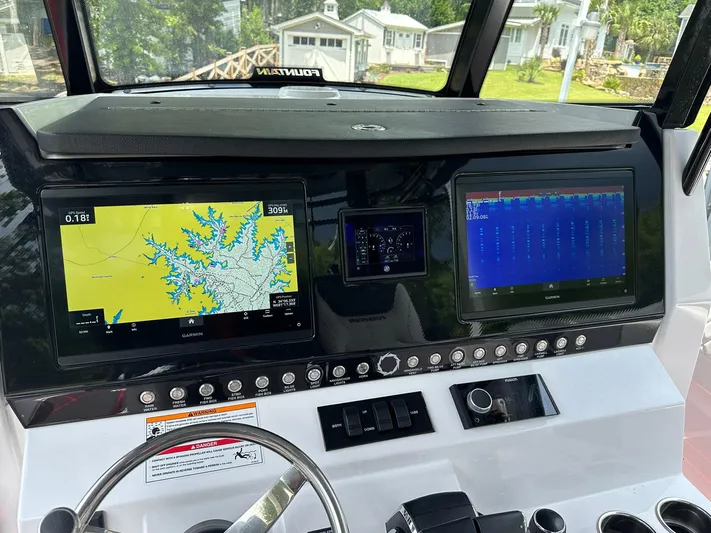  Yacht Photos Pics 2024 Fountain 32 NX dashboard with navigation and control screens, steering wheel, and control panel.