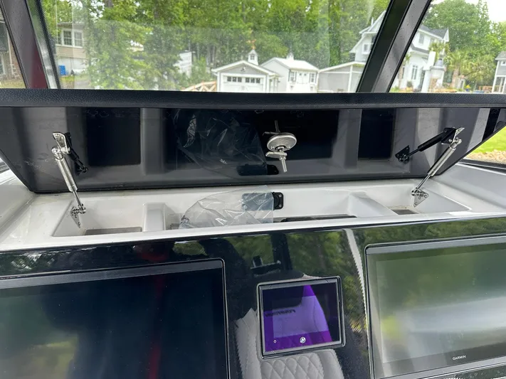  Yacht Photos Pics 2024 Fountain 32 NX boat dashboard with open storage compartment and electronic displays.