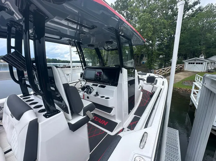  Yacht Photos Pics 2024 Fountain 32 NX boat interior with modern controls, docked by a lakeside.
