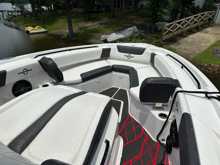  Yacht Photos Pics 2024 Fountain 32 NX boat interior with white and black seating, docked by a lakeside.
