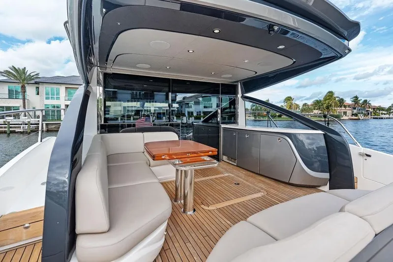 Hullabaloo Yacht Photos Pics Luxurious 2021 Princess V55 yacht with elegant seating and sleek design on a sunny waterfront.