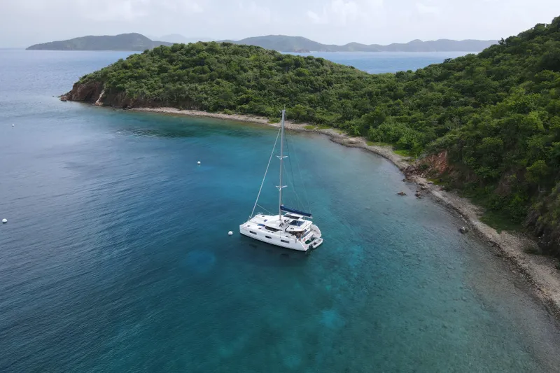 Artemis Yacht Photos Pics 2023 Lagoon 46 catamaran anchored in a serene, tropical bay with lush green hills.