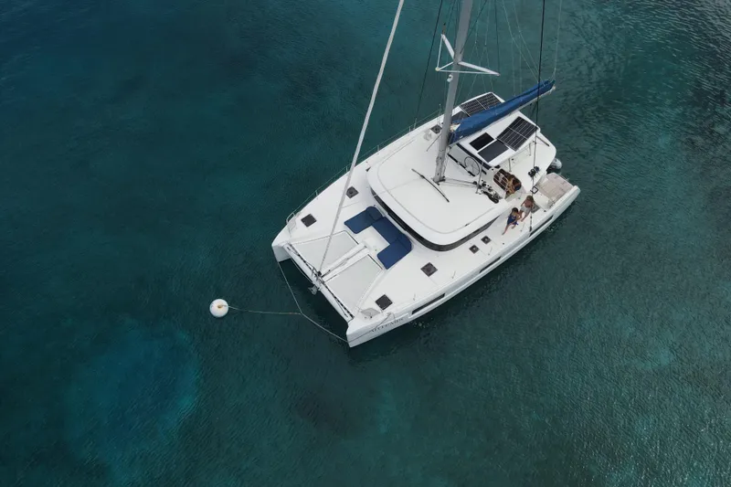 Artemis Yacht Photos Pics Aerial view of 2023 Lagoon 46 catamaran anchored in clear blue water.
