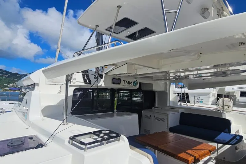 Artemis Yacht Photos Pics 2023 Lagoon 46 catamaran deck with seating and table under clear blue sky.
