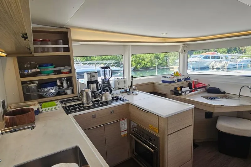 Artemis Yacht Photos Pics Modern kitchen interior of 2023 Lagoon 46 catamaran with appliances and scenic window view.