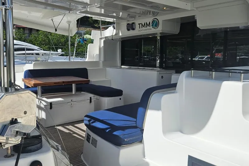 Artemis Yacht Photos Pics 2023 Lagoon 46 yacht interior with blue seating and wooden table.