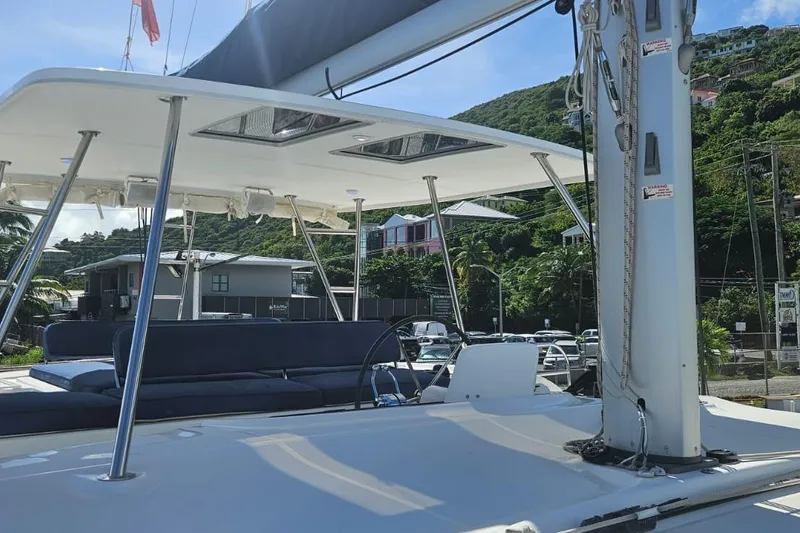 Artemis Yacht Photos Pics 2023 Lagoon 46 catamaran deck with seating, docked near lush hillside.