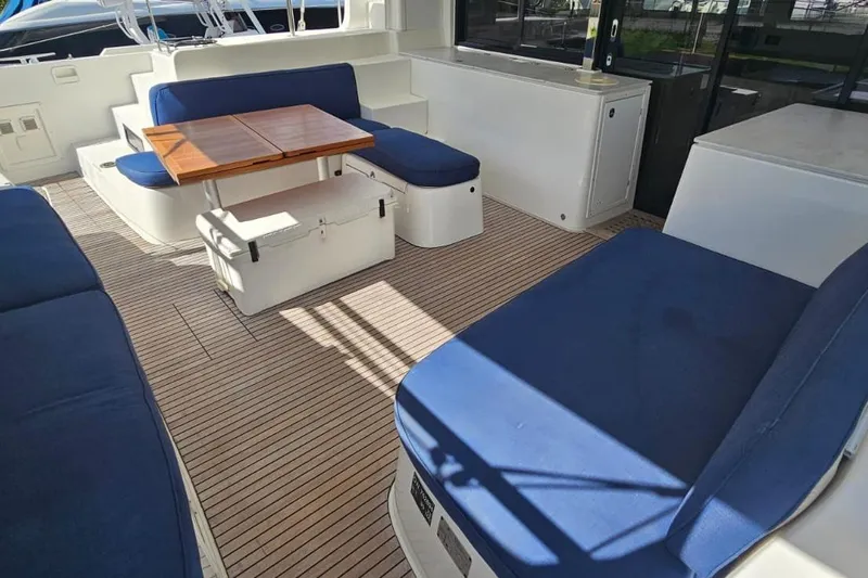 Artemis Yacht Photos Pics Spacious seating area on 2023 Lagoon 46 yacht with blue cushions and wooden table.