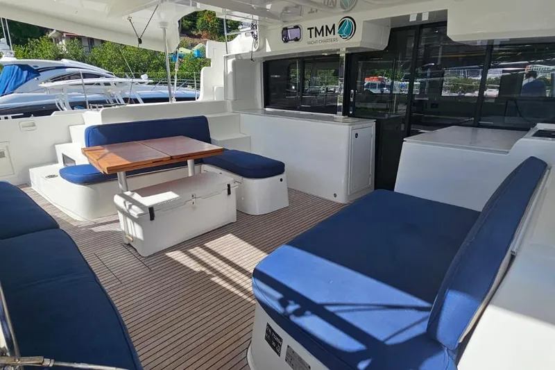 Artemis Yacht Photos Pics 2023 Lagoon 46 yacht interior with blue seating and wooden table.