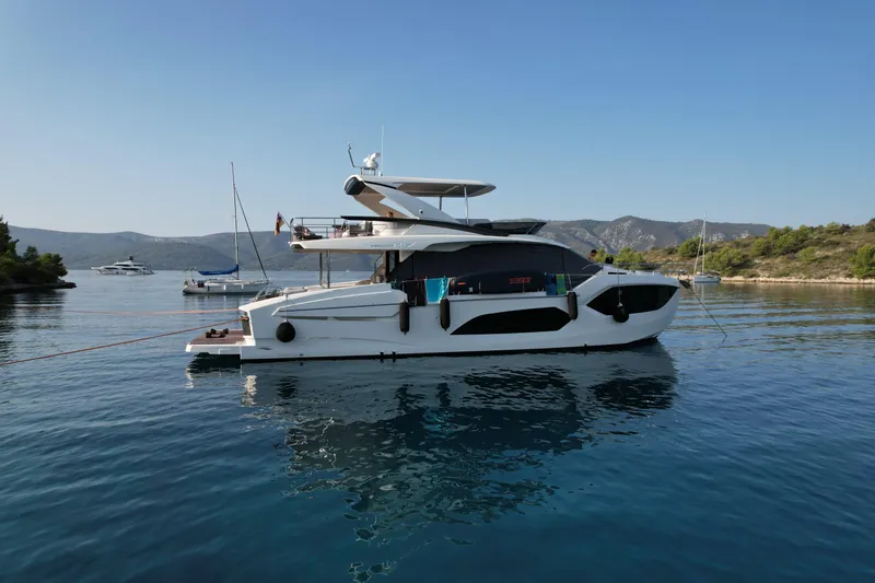  Yacht Photos Pics 2024 Absolute 60 Fly yacht anchored in serene waters, surrounded by scenic hills.