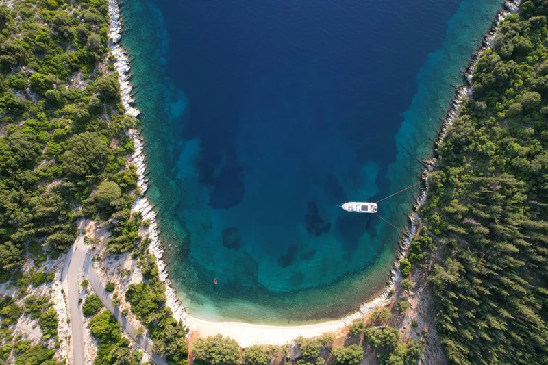  Yacht Photos Pics Aerial view of 2024 Absolute 60 Fly yacht anchored in a serene, forest-lined cove.