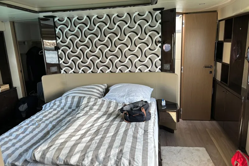  Yacht Photos Pics Luxurious bedroom interior of 2024 Absolute 60 Fly yacht with modern decor and striped bedding.