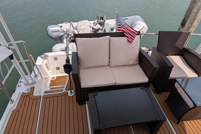 Elena Yacht Photos Pics Bayliner 4088 yacht deck with seating, American flag, and Honda outboard motor, 2000 model.