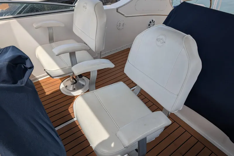 Elena Yacht Photos Pics Two white captain chairs on a 2000 Bayliner 4088 boat with wooden deck.