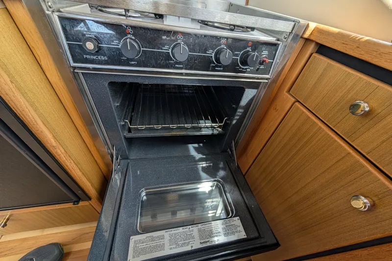 Elena Yacht Photos Pics Open oven in 2000 Bayliner 4088 yacht kitchen, featuring wooden cabinetry and modern controls.