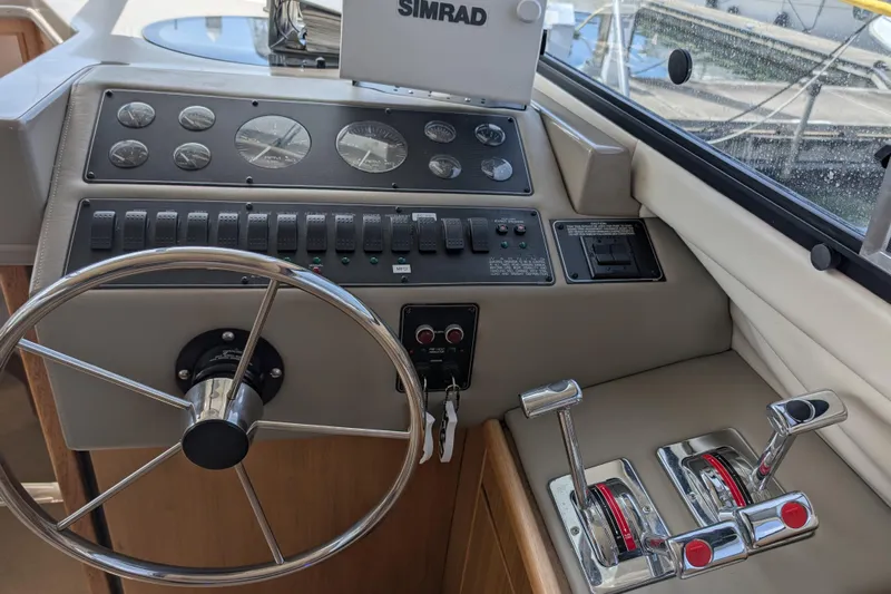 Elena Yacht Photos Pics Control panel of a 2000 Bayliner 4088 boat with steering wheel and throttle levers.