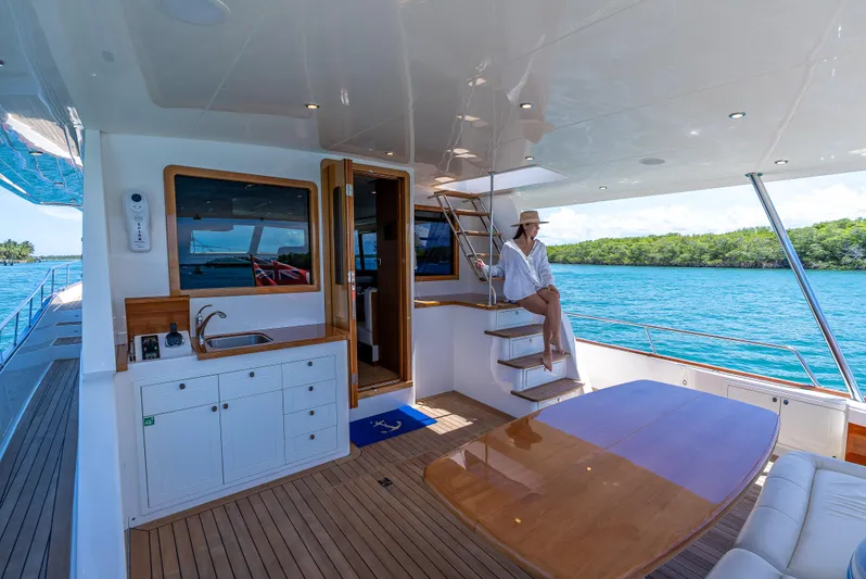 Tonic Yacht Photos Pics Luxury 2018 Grand Banks GB60 yacht interior with woman relaxing, featuring elegant wood finishes.
