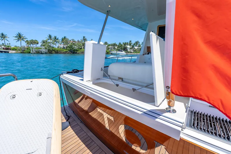 Tonic Yacht Photos Pics 2018 Grand Banks GB60 yacht with red flag, docked near tropical shoreline.