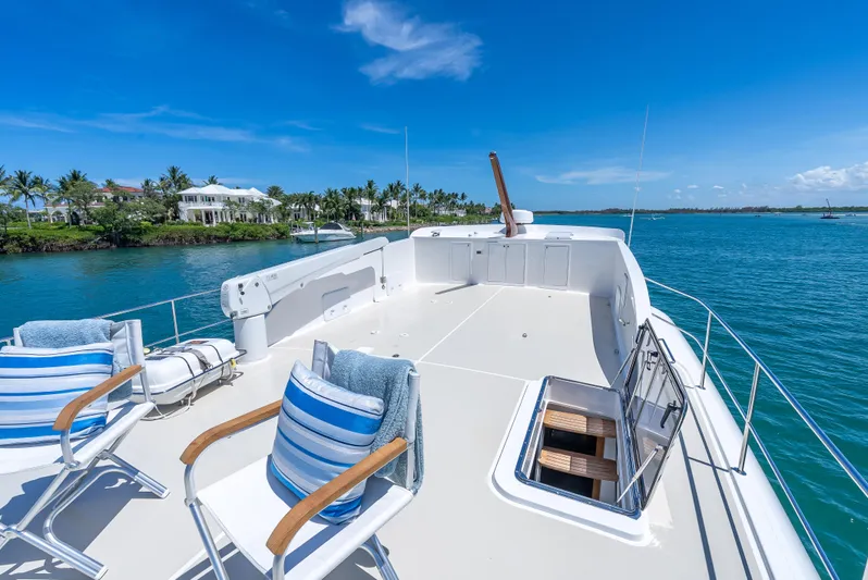 Tonic Yacht Photos Pics Luxurious 2018 Grand Banks GB60 yacht deck with chairs, overlooking serene blue waters and coastal homes.
