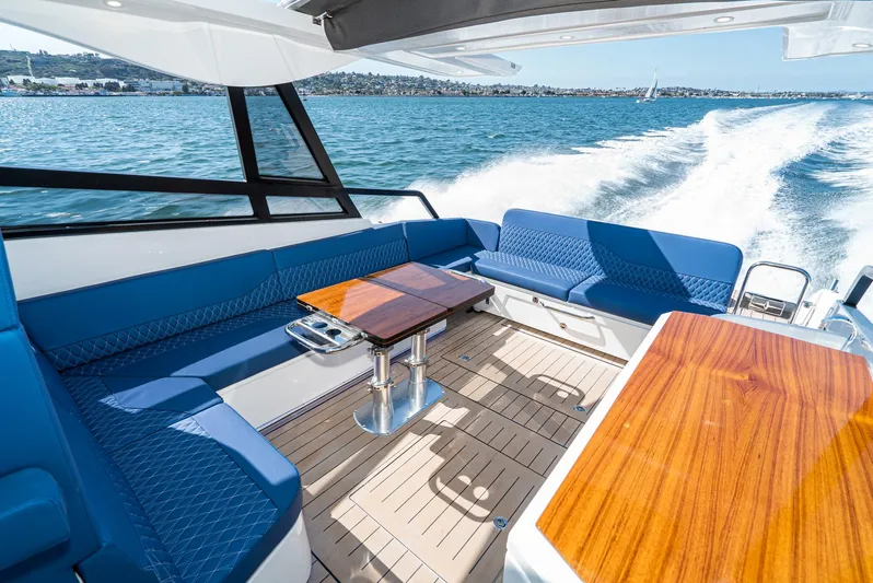 On Its Way Yacht Photos Pics 2024 Bavaria Vida 33 yacht interior with blue seating and wooden tables on open water.