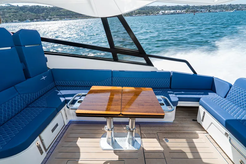 On Its Way Yacht Photos Pics 2024 Bavaria Vida 33 yacht interior with blue seating and wooden table on open water.