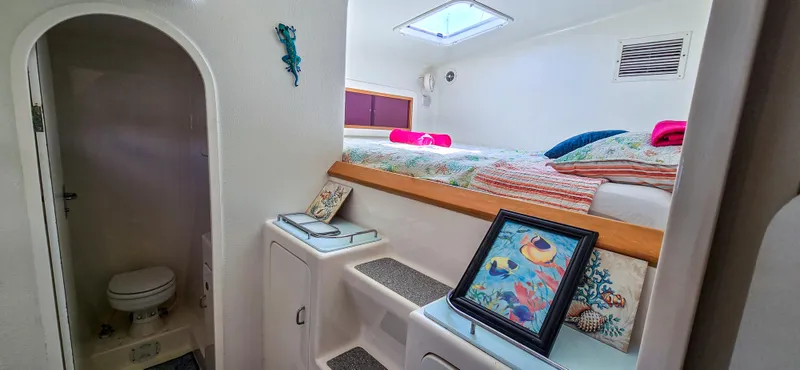 Makai Yacht Photos Pics Cozy cabin interior of 1997 Voyage Mayotte 50 yacht with bed, artwork, and bathroom.