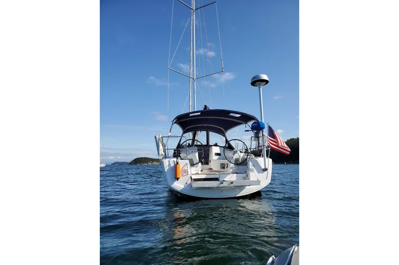 Imagine Yacht Photos Pics 2017 Jeanneau Sun Odyssey 349 sailboat on calm water, rear view with American flag.