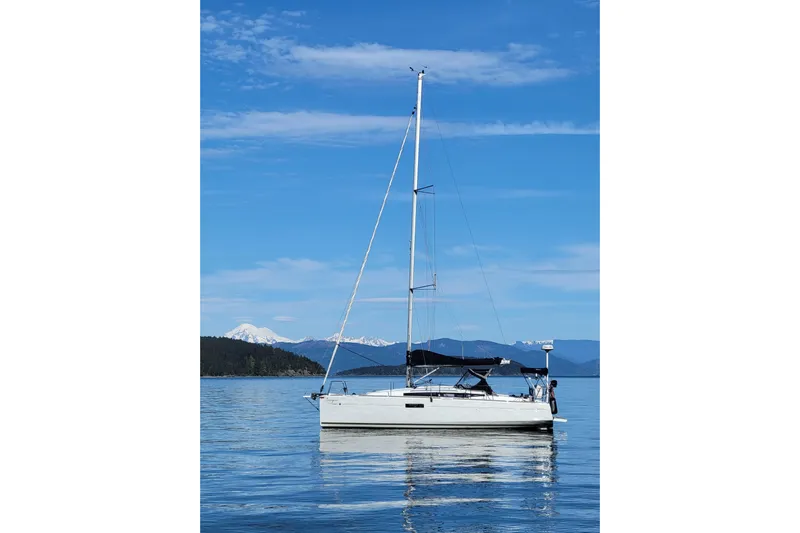 Imagine Yacht Photos Pics 2017 Jeanneau Sun Odyssey 349 sailboat on calm water with mountain backdrop.