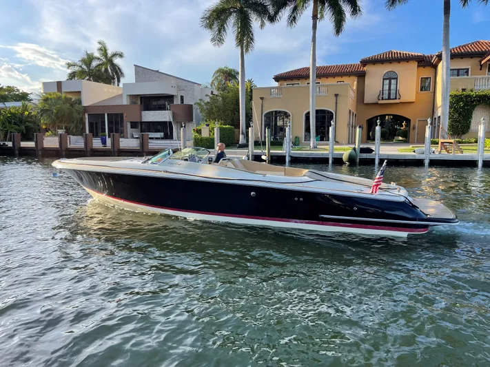 Grato Yacht Photos Pics 2015 Chris-Craft 32 Launch boat cruising near waterfront homes and palm trees.