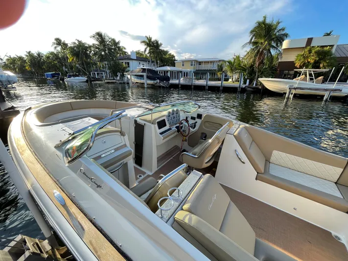 Grato Yacht Photos Pics 2015 Chris-Craft 32 Launch boat docked by waterfront homes, featuring luxurious seating and controls.