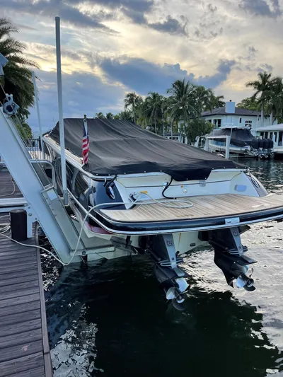 Grato Yacht Photos Pics 2015 Chris-Craft 32 Launch boat docked with cover, surrounded by palm trees and waterfront homes.