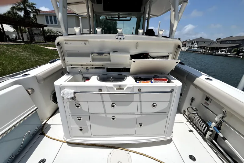  Yacht Photos Pics 2019 Boston Whaler 330 Outrage boat with open storage compartments and sink, docked by waterfront homes.