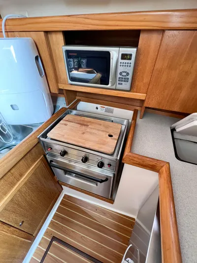 Cheers Yacht Photos Pics Catalina 350 yacht kitchen with stove, microwave, and wooden cabinetry, 2006 model.