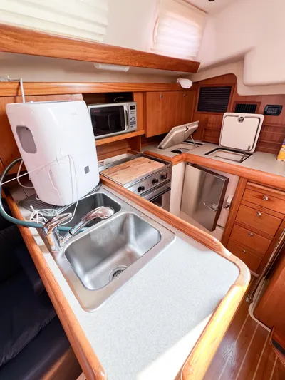 Cheers Yacht Photos Pics 2006 Catalina 350 yacht kitchen with sink, microwave, and wooden cabinetry.