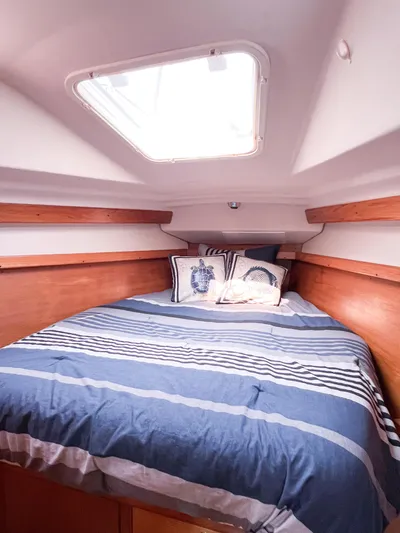 Cheers Yacht Photos Pics Cozy cabin interior of 2006 Catalina 350 sailboat with striped bedding and wooden accents.