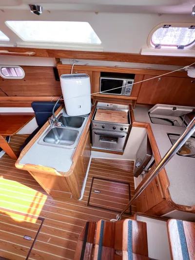 Cheers Yacht Photos Pics Interior of 2006 Catalina 350 sailboat with kitchen, sink, stove, and wooden flooring.