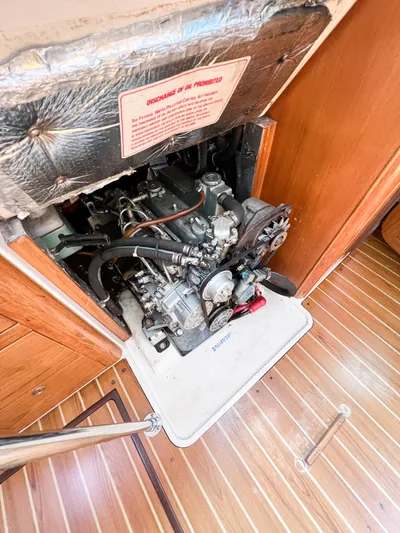 Cheers Yacht Photos Pics Engine compartment of a 2006 Catalina 350 sailboat, showcasing mechanical components and wooden flooring.