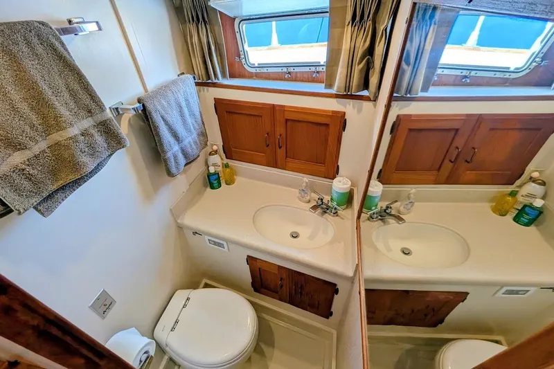 Innovation Yacht Photos Pics 1978 Tollycraft 54 Custom Cockpit Motor Yacht bathroom with sink, mirror, and wooden cabinets.