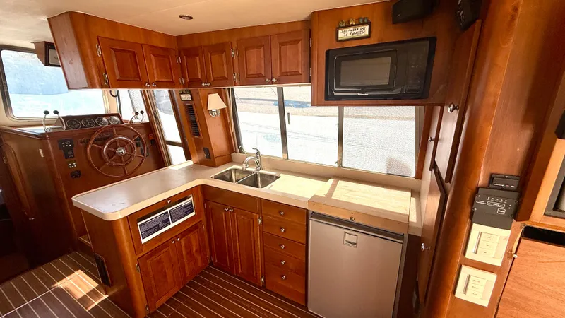 Sabiha Yacht Photos Pics Interior of 2004 Mainship 400 Trawler with wooden kitchen and helm area.