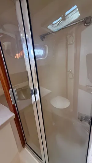 Sabiha Yacht Photos Pics Shower in 2004 Mainship 400 Trawler, featuring glass enclosure and skylight.