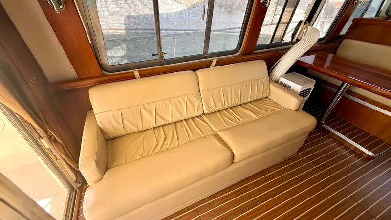Sabiha Yacht Photos Pics Interior of 2004 Mainship 400 Trawler with leather sofa and wood flooring.