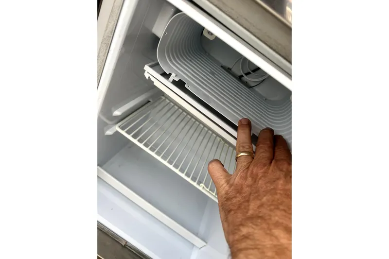 New Trade-in- All Offers & Trades Welcome Yacht Photos Pics Hand inspecting a refrigerator inside a 2018 Scout 350 LXF boat.