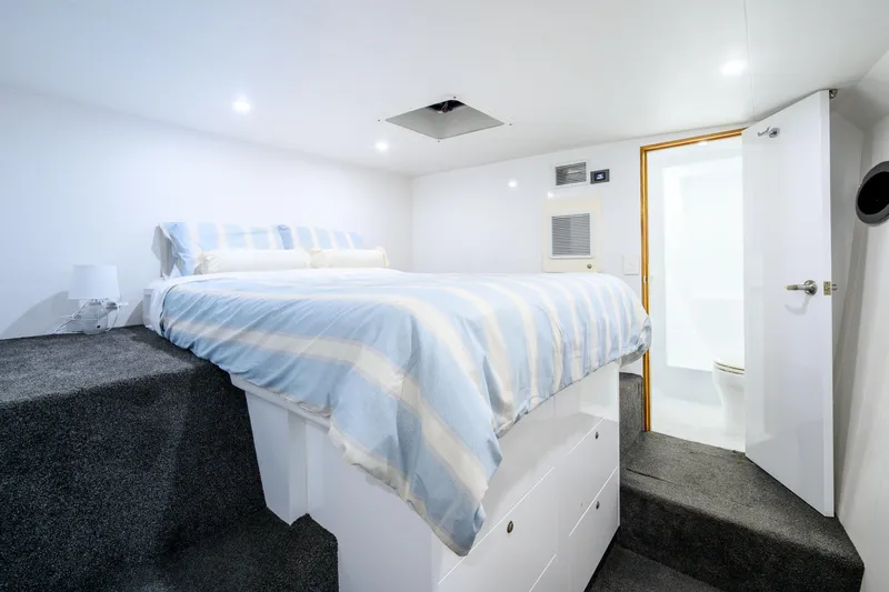 One Off Yacht Photos Pics Luxurious bedroom interior of 2019 Coral Coast 62 Power Catamaran with striped bedding and ensuite bathroom.