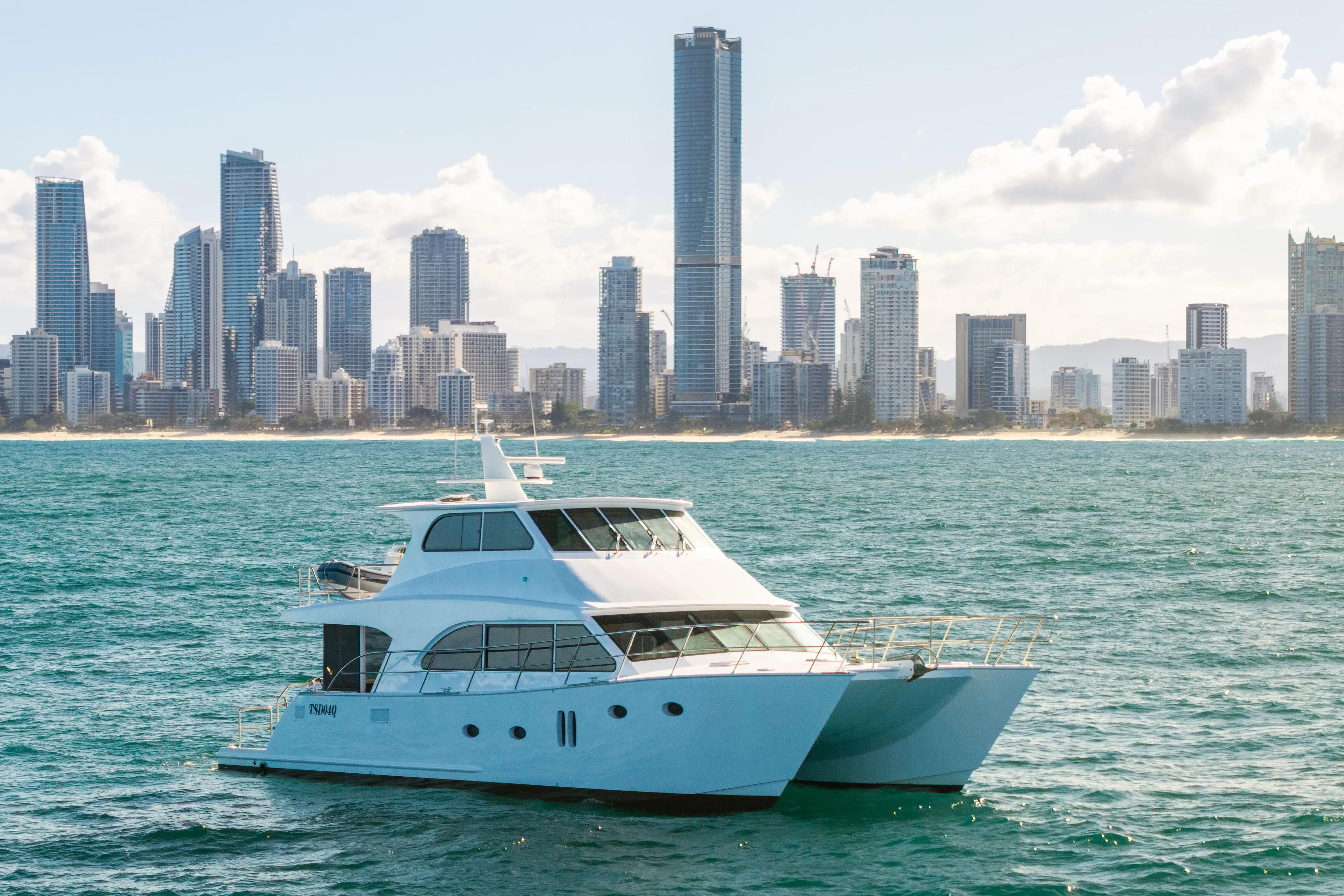 One Off Yacht Photos Pics 2019 Coral Coast 62 Power Catamaran on ocean, city skyline in background.