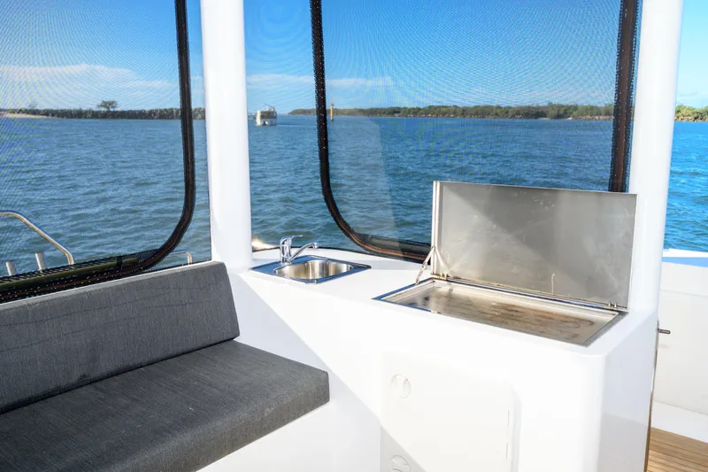One Off Yacht Photos Pics Interior of 2019 Coral Coast 62 Power Catamaran with sink and seating, overlooking water.