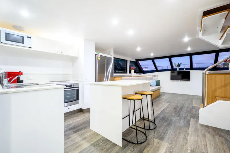 One Off Yacht Photos Pics Modern kitchen and lounge area in 2019 Coral Coast 62 Power Catamaran, featuring sleek design and ample lighting.